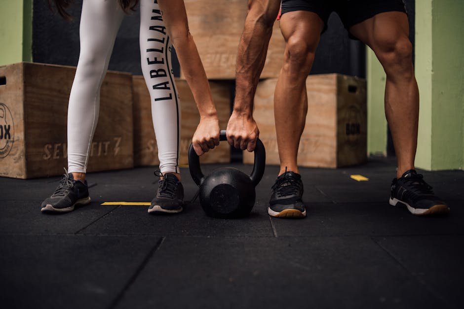 A man and woman engaging in CrossFit training with a kettlebell at an indoor gym in Brazil.