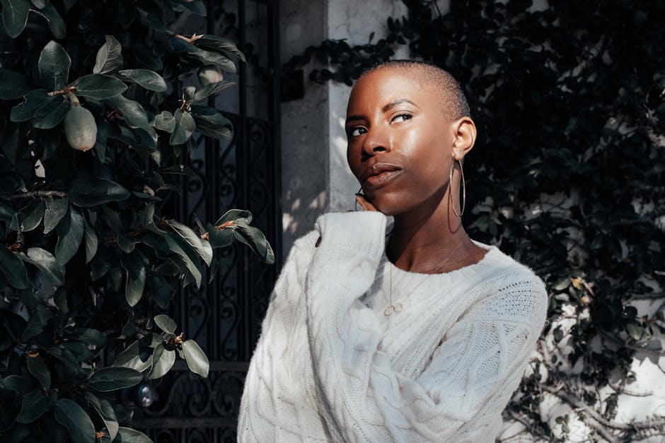 Striking portrait of an African American woman in a knit sweater, standing pensively outdoors.