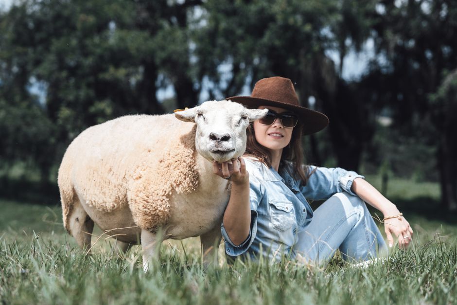 A woman and sheep relaxing in a serene rural landscape on a sunny day.