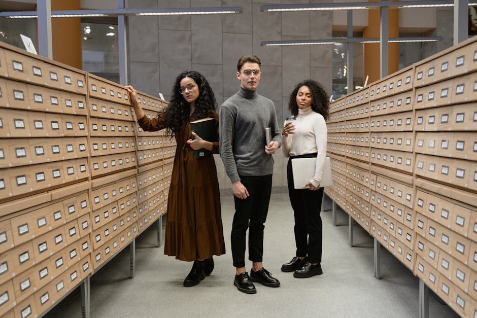 Three diverse students researching in a modern library's card catalog center.