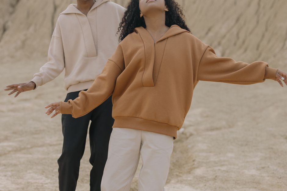 Two fashionable individuals pose in stylish streetwear outdoors.