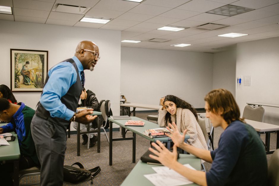 A professor interacts with college students during a lively classroom discussion.