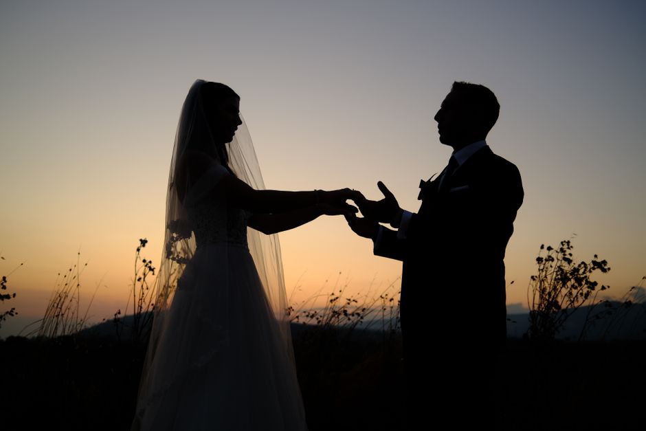 A silhouette of a bride and groom holding hands at sunset, symbolizing love and togetherness.