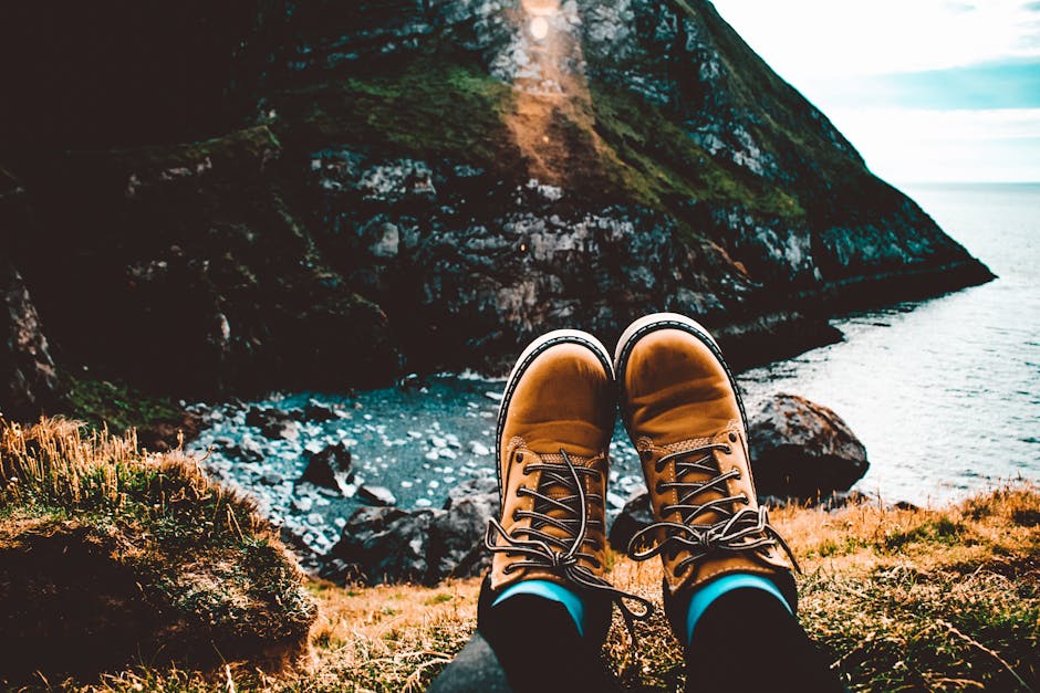 A person relaxes in hiking boots overlooking stunning coastal cliffs and ocean view.