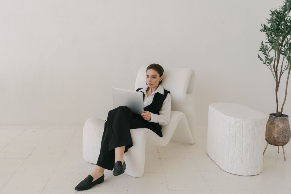 Businesswoman in a modern, minimalist setting working on a laptop indoors.