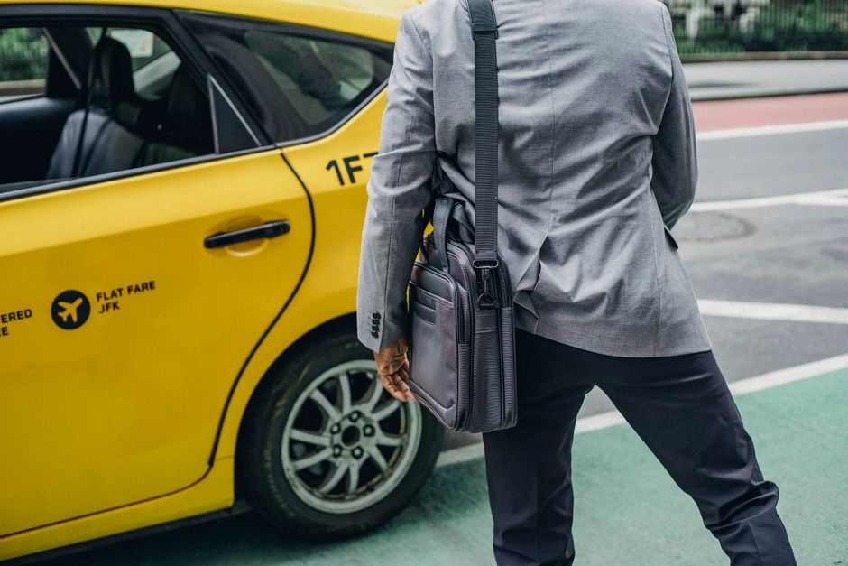 Back view of crop anonymous male standing near bright yellow automobile with inscriptions