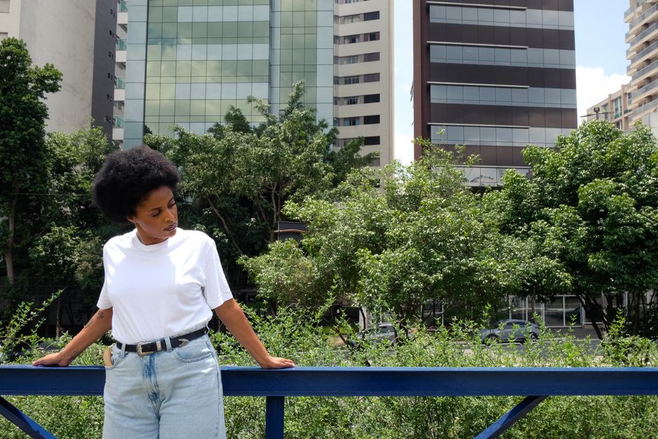 Stylish woman in white t-shirt and jeans against São Paulo skyline.