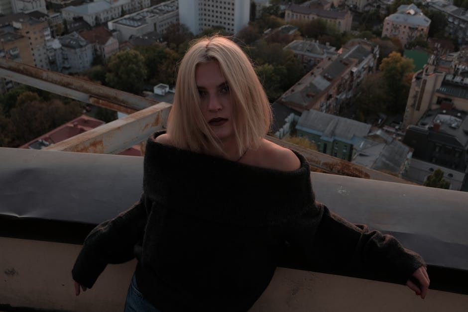 Moody female portrait on a rooftop with urban background at dusk.