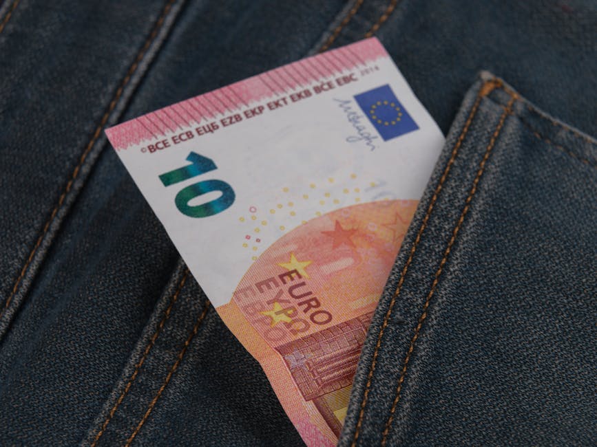 Close-up of a 10 euro banknote sticking out from a denim pocket.
