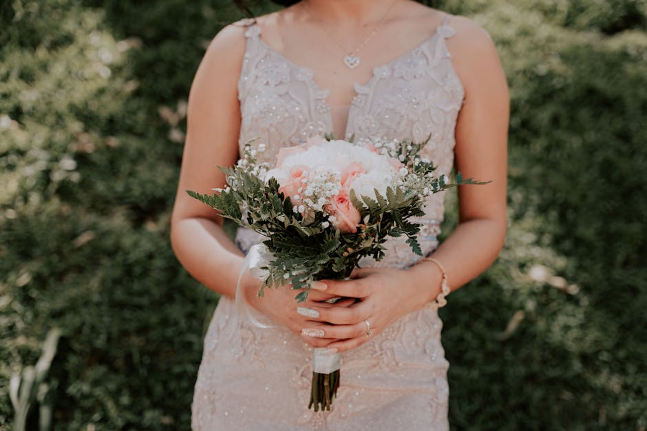 Close-up of a bride holding a beautiful bouquet in a sunlit garden setting.