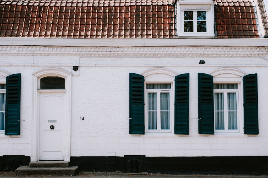 Charming white facade with blue shutters on a European style cottage. Ideal for architectural content.